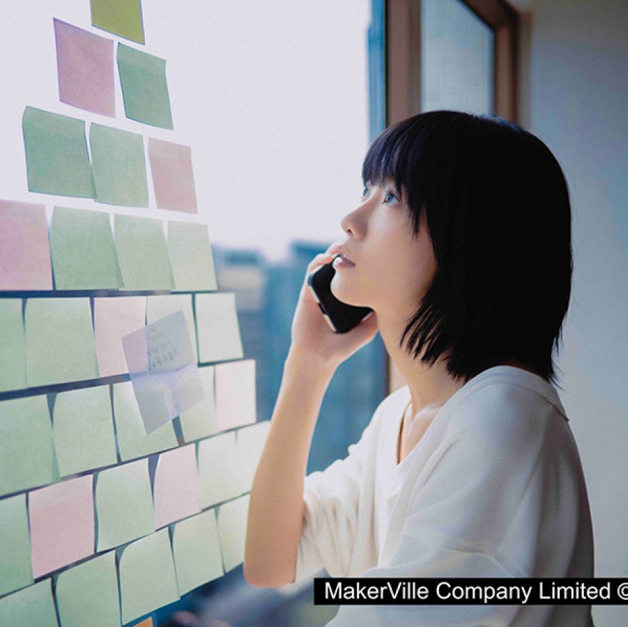 Young woman Tou Ka-tou (Fish Liew) looks out of a window that has been covered in post-it notes while holding a phone to her ear, in a scene from Cicada Cycle. 
